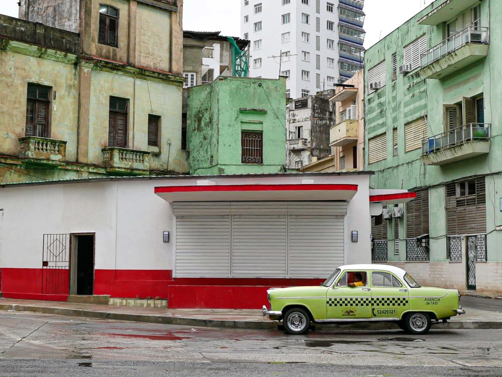 A lone taxi driver waiting in the colorful streets of Havana