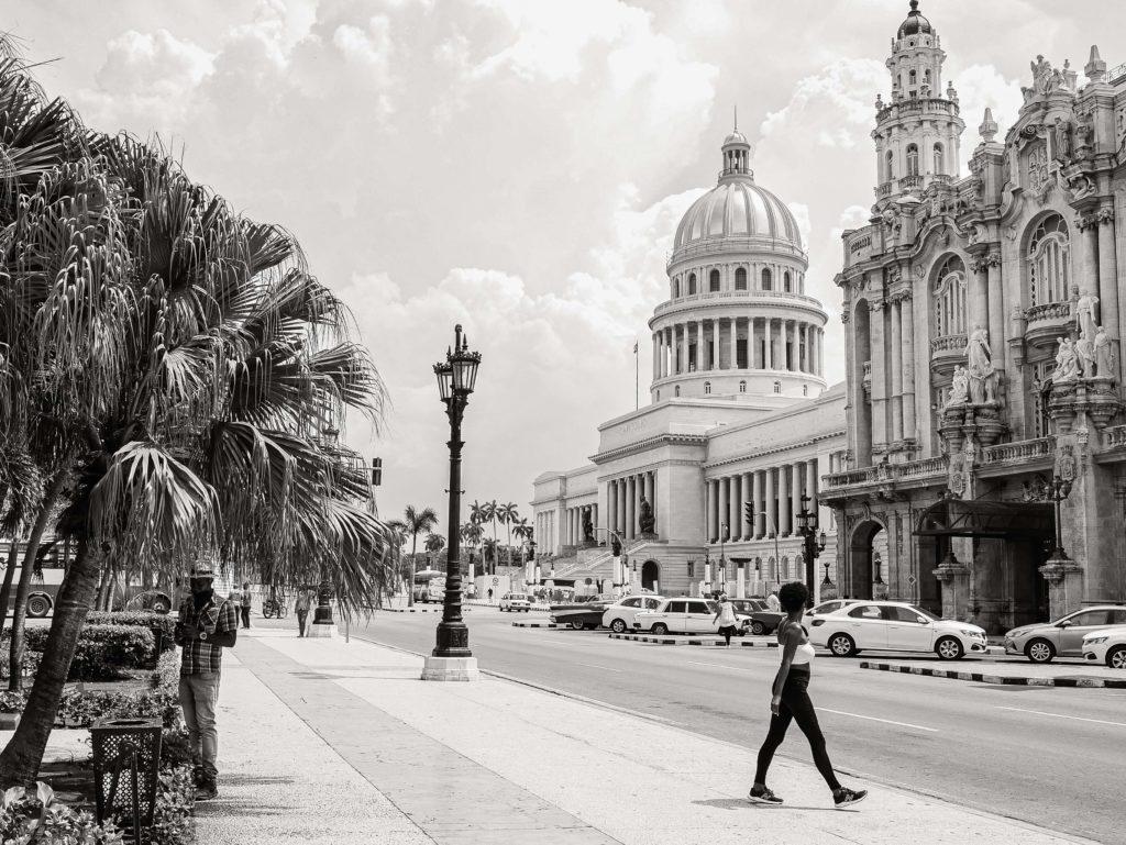 A woman walks along the avenue in Havana, with the Capitol building rising in the background