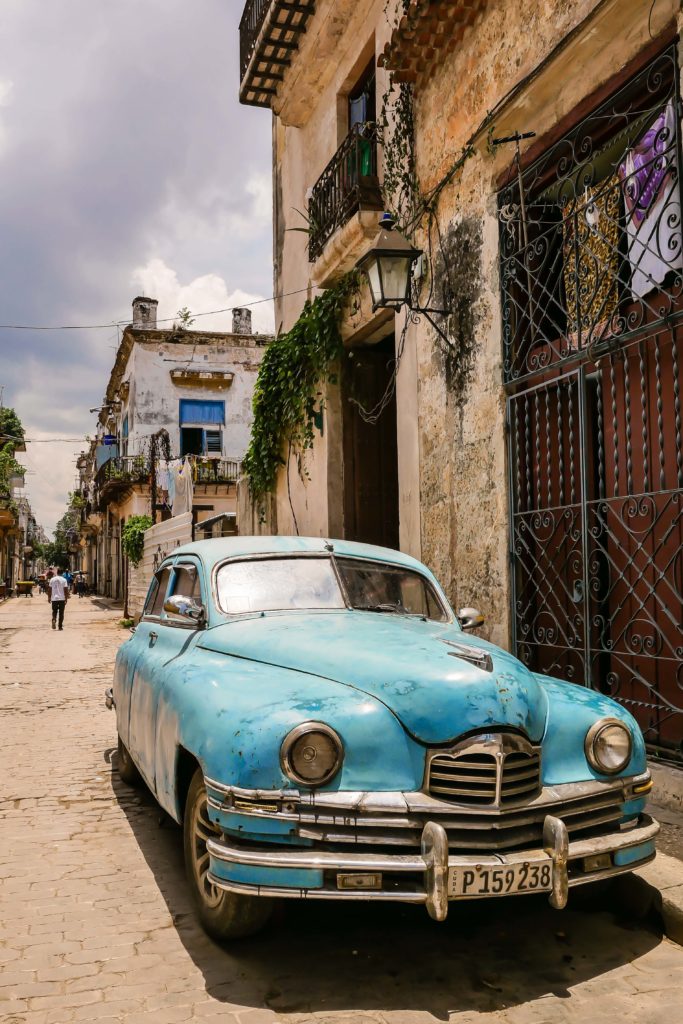 A classic blue car parked along a narrow street in Havana