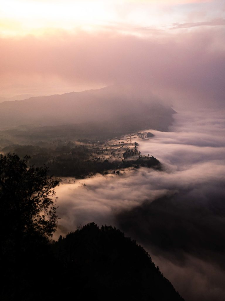 A foggy sunrise unfolding above a small village near Mount Bromo