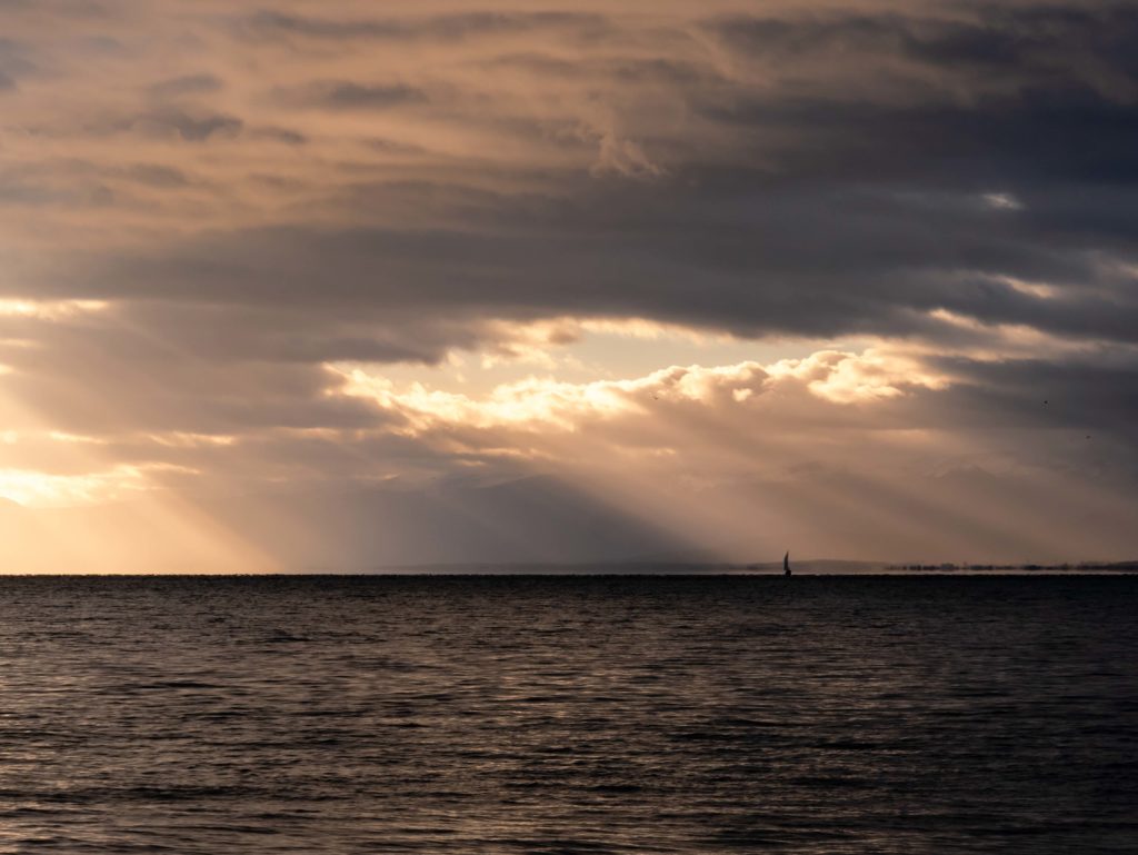 Facing east, a lone boat glows beneath a stormy sky over Lake Geneva