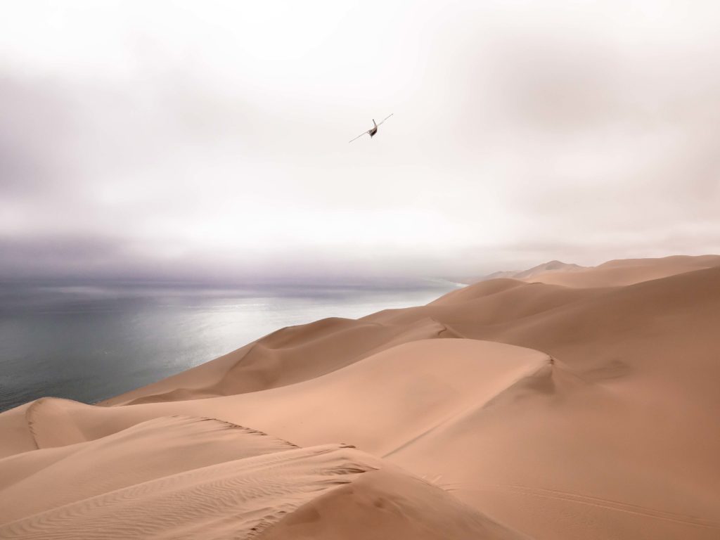 A lone plane crossing the vast skies above Namibia’s Skeleton Coast