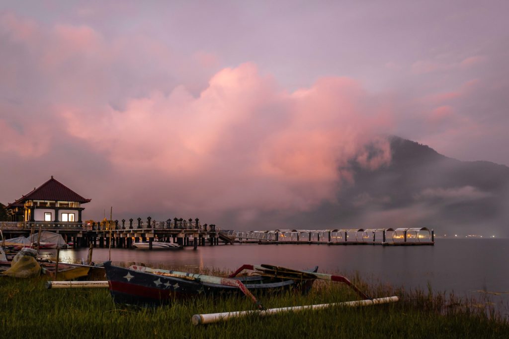 Golden clouds drifting above the calm waters and temple shores of a mountain lake in Bali, Indonesia