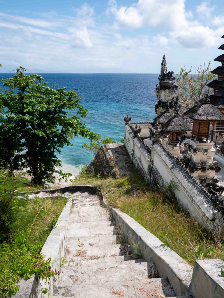 Stone staircase leading to Pura Dalem Ped temple overlooking the turquoise sea in Nusa Penida, Indonesia