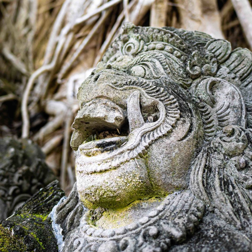 Close-up of a weathered stone Barong statue covered with moss in Indonesia