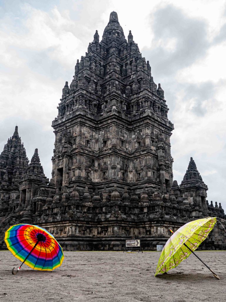 Colorful umbrellas on the sand in front of Prambanan Temple, a Hindu complex near Yogyakarta
