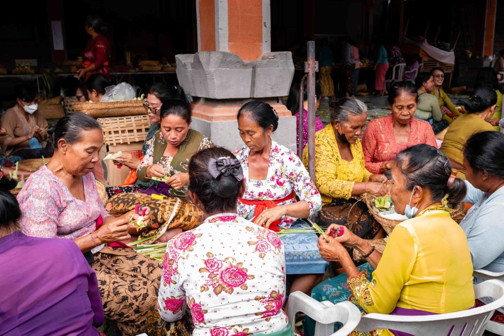 Balinese women crafting traditional palm leaf offerings during a temple ceremony in Ubud