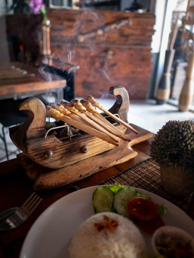 Traditional chicken satay served on a wooden grill with rice and vegetables in Yogyakarta