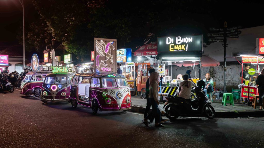 Colorful illuminated odong-odong cars and street food stalls at night in Yogyakarta