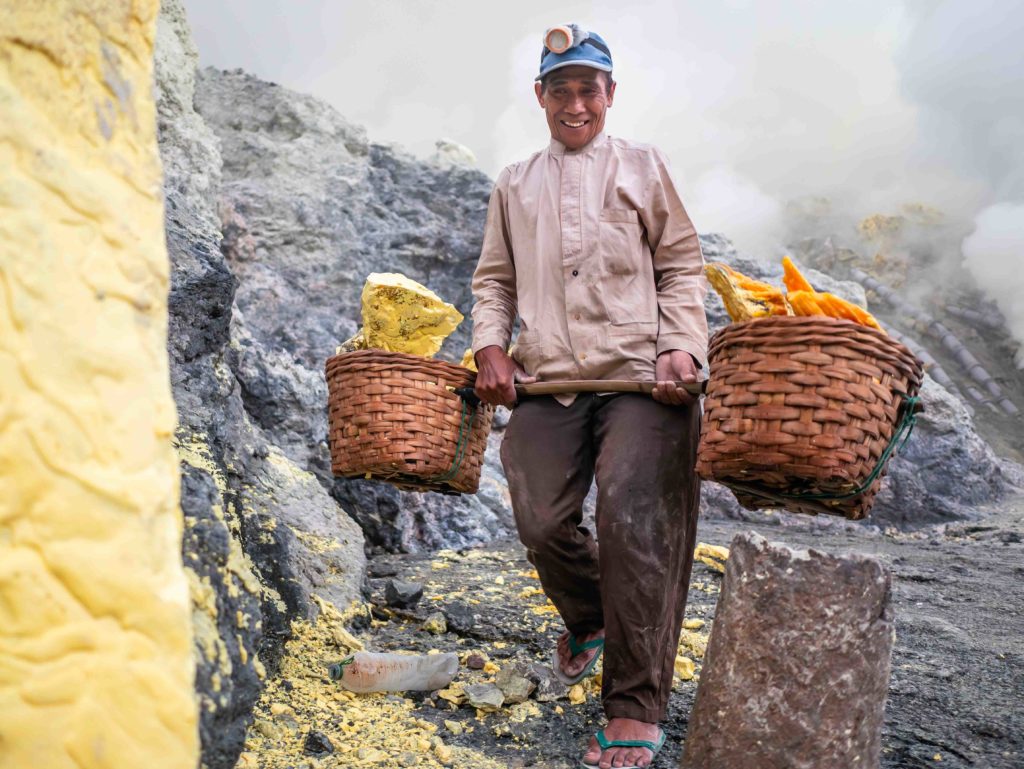 Sulfur miner carrying baskets of yellow sulfur from the Kawah Ijen crater in East Java