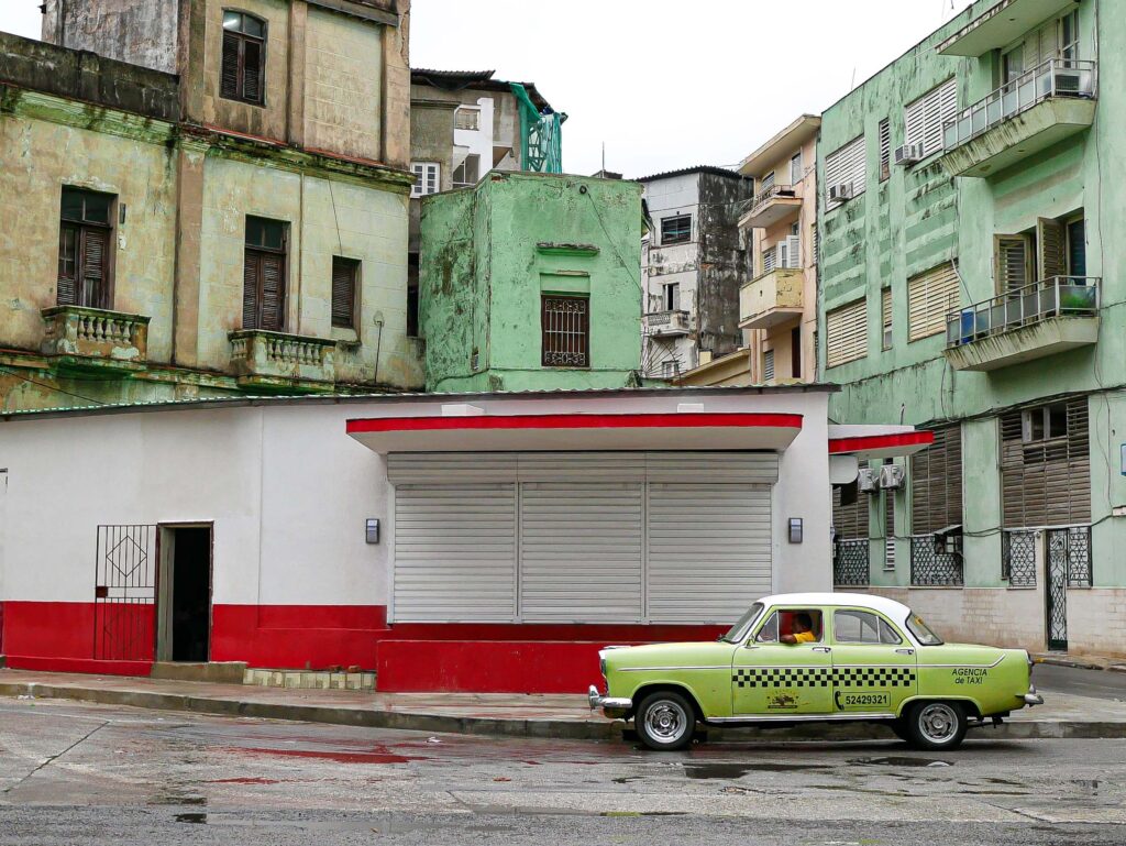 A lone taxi driver waiting in the colorful streets of Havana